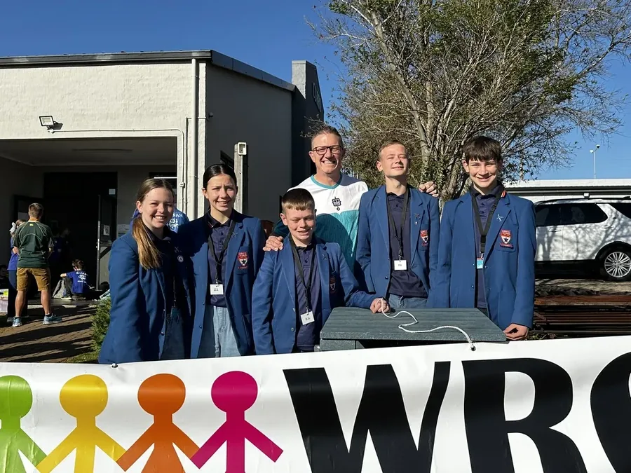 Robotics League students in school blazers at the WRO banner