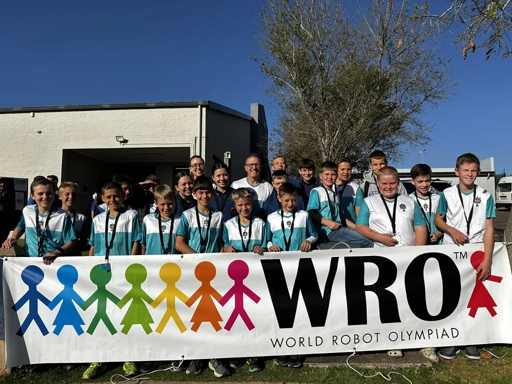 Full Robotics League squad with coach at the WRO South Africa banner